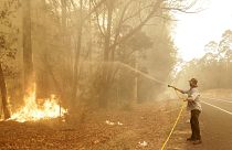 رجل يستخدم خرطوم مياه لمحاربة حريق بالقرب من مورويا في أستراليا، 4 يناير 2020