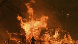 Un pompier face à une maison en feu en Australie ; Celeste Barber récolte plus de 20 millions d'euros pour aider les pompiers