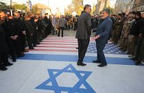 Iraqi paramilitaries walk on pictures Trump and Netanyahu