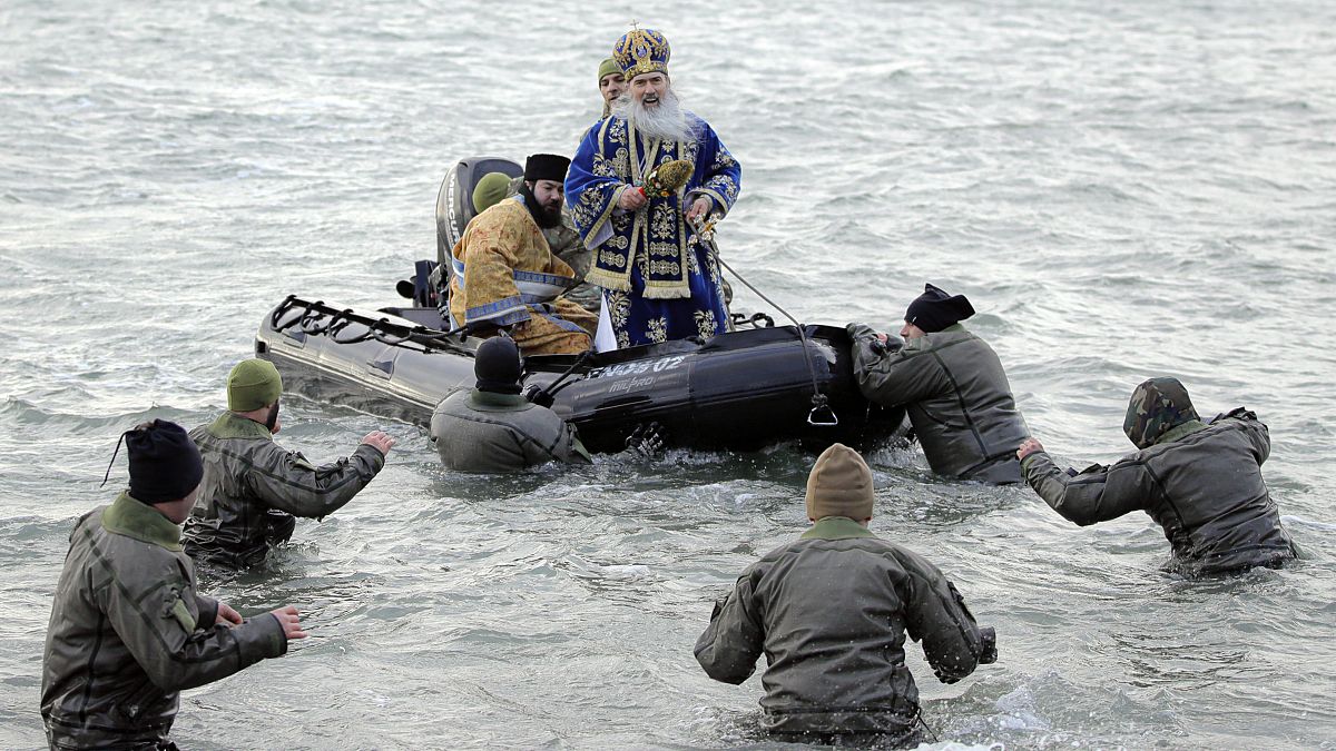Military divers walk to a boat carrying Orthodox archbishop Teodosie during an Epiphany religious service in Constanta, Romania. 6 January, 2020. 