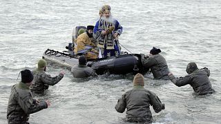 Military divers walk to a boat carrying Orthodox archbishop Teodosie during an Epiphany religious service in Constanta, Romania. 6 January, 2020. 