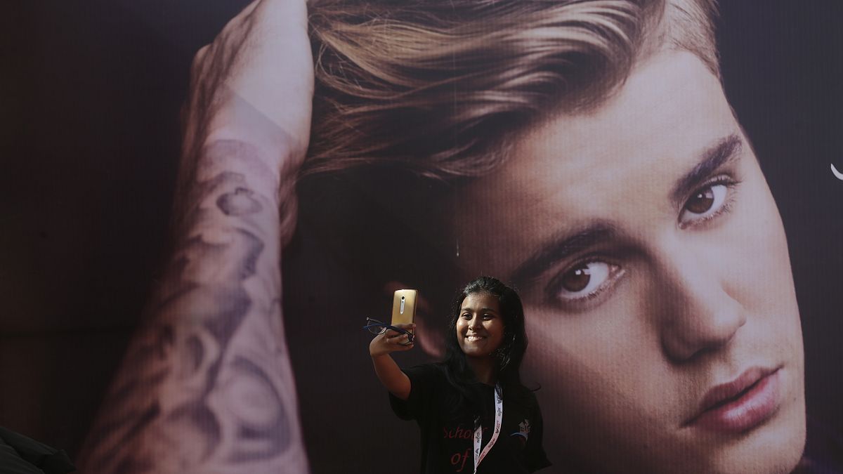إحدى معجبات المغني الكندي جاستن بيبر تأخذ صورة سيلفي أمام صورته قبل حفل موسيقي له في مومباي، مايو 2017.