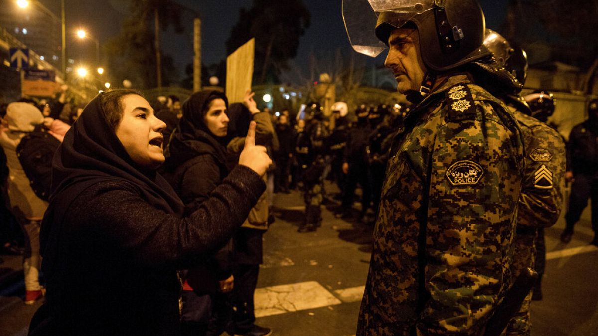 An Iranian woman at a vigil for victims of the Ukraine plane disaster talks to policeman at Amri Kabir University, Tehran