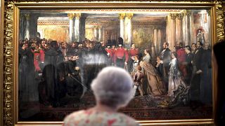 Queen Elizabeth II looks at a painting of Queen Victoria