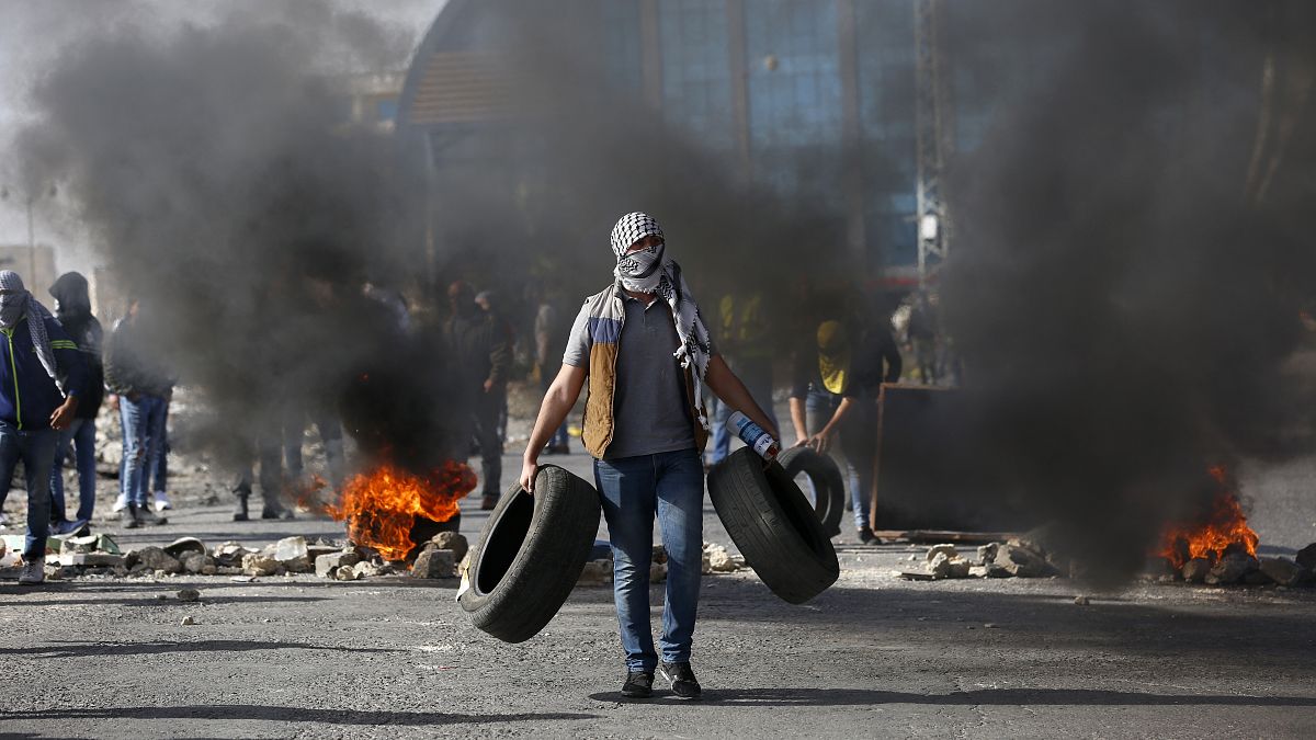 متظاهر فلسطيني يحمل إطارات خلال مظاهرات في رام الله
