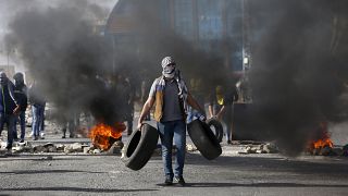متظاهر فلسطيني يحمل إطارات خلال مظاهرات في رام الله