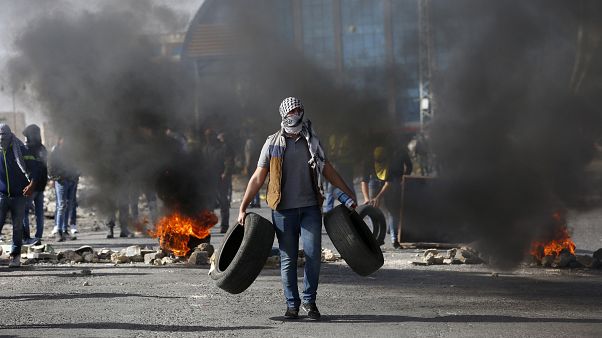 متظاهر فلسطيني يحمل إطارات خلال مظاهرات في رام الله متظاهر فلسطيني يحمل إطارات خلال مظاهرات في رام الله