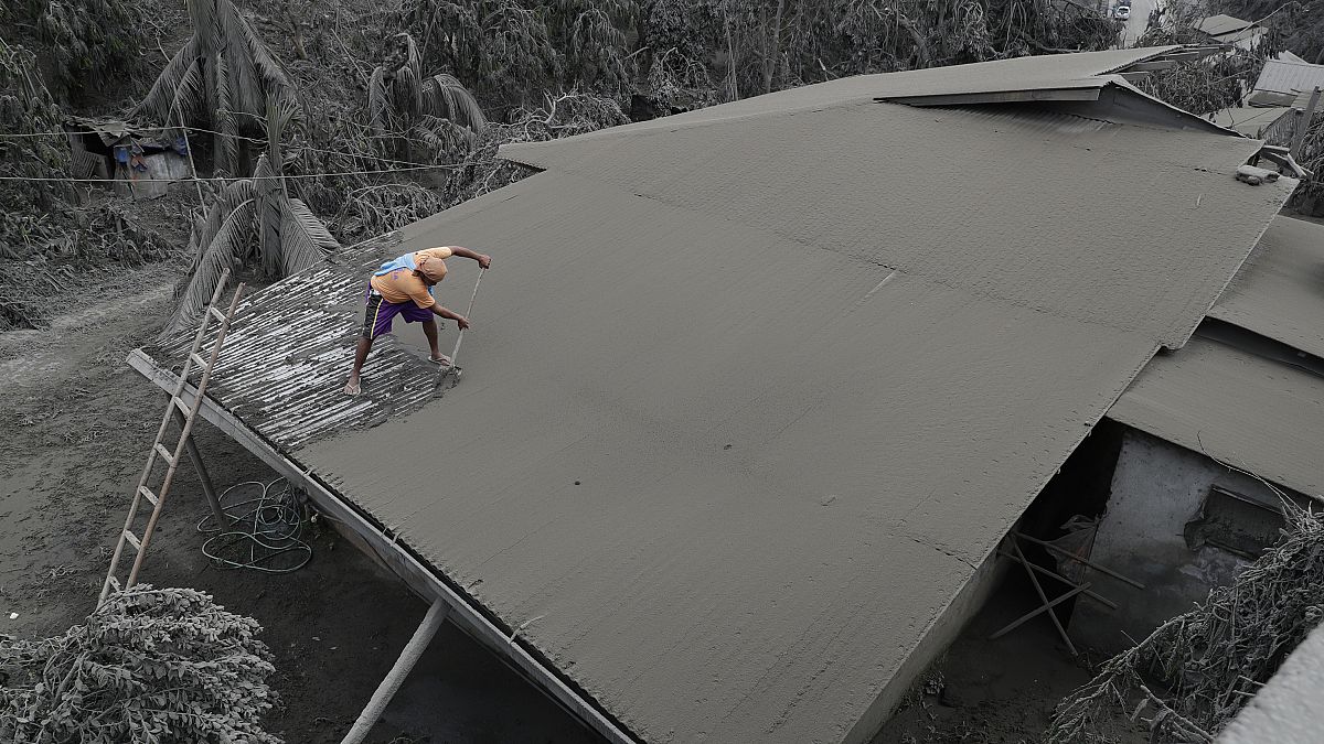 A resident clears volcanic ash from his roof in Laurel, Batangas province, the southern Philippines on Tuesday, 14 January, 2020