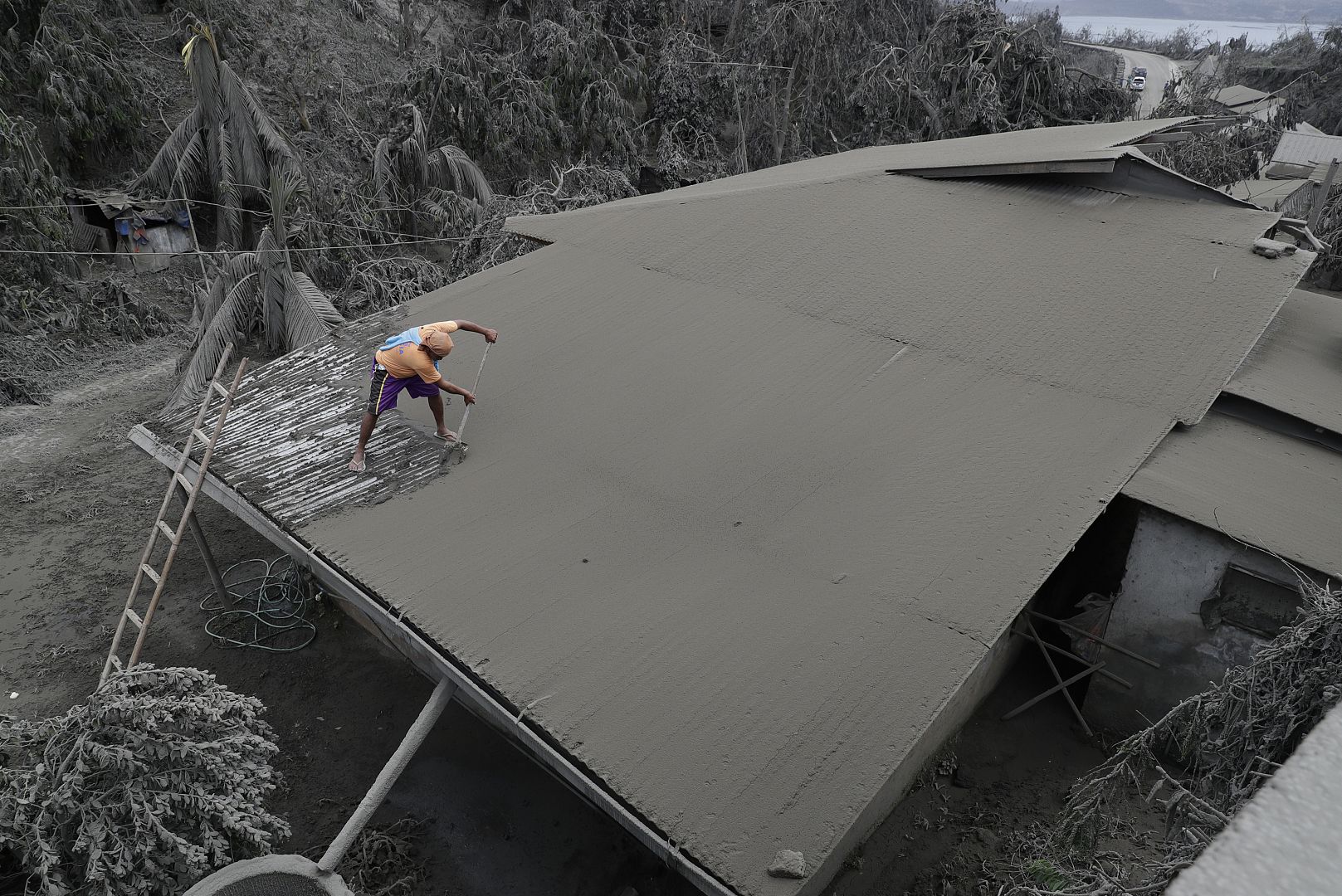 A resident clears volcanic ash from his roof in Laurel, Batangas province, the southern Philippines on Tuesday, 14 January 2020