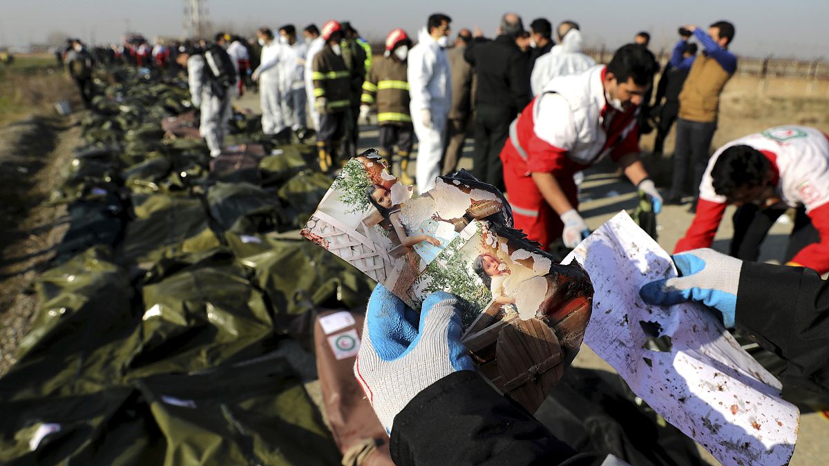 أحد عمال الإنقاذ يحمل صورا وجدت في موقع تحطم الطائرة الأوكرانية في طهران - إيران