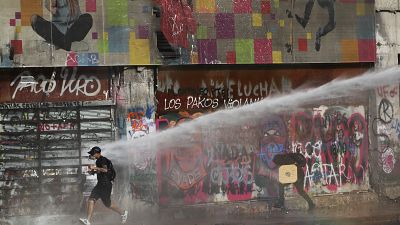 Un manifestant tente d'échapper à un jet de canon à eau, Santiago, Chili, le 17 janvier 2020