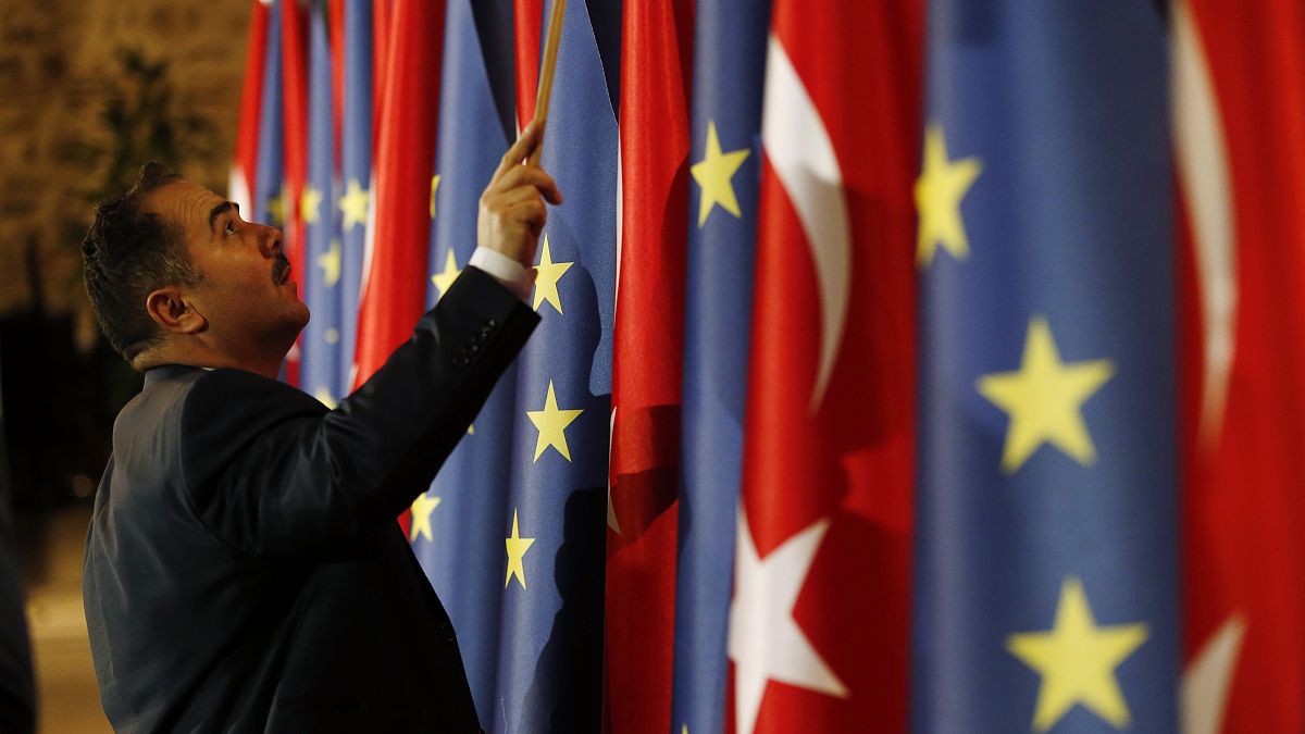 An official adjusts Turkey's and European flags prior to a meeting between EU and Turkey
