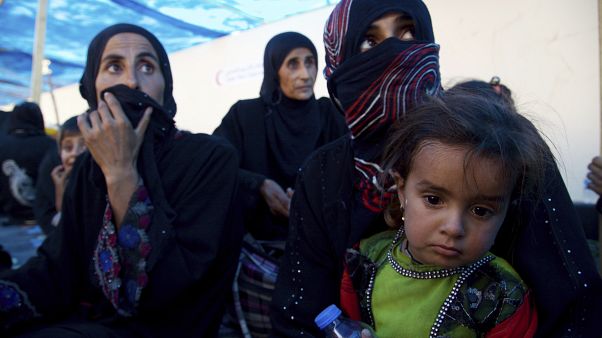 صورة للمشردين من النساء والأطفال يجلسون على الأرض عند نقطة تجميع غرب الموصل صورة للمشردين من النساء والأطفال يجلسون على الأرض عند نقطة تجميع غرب الموصل