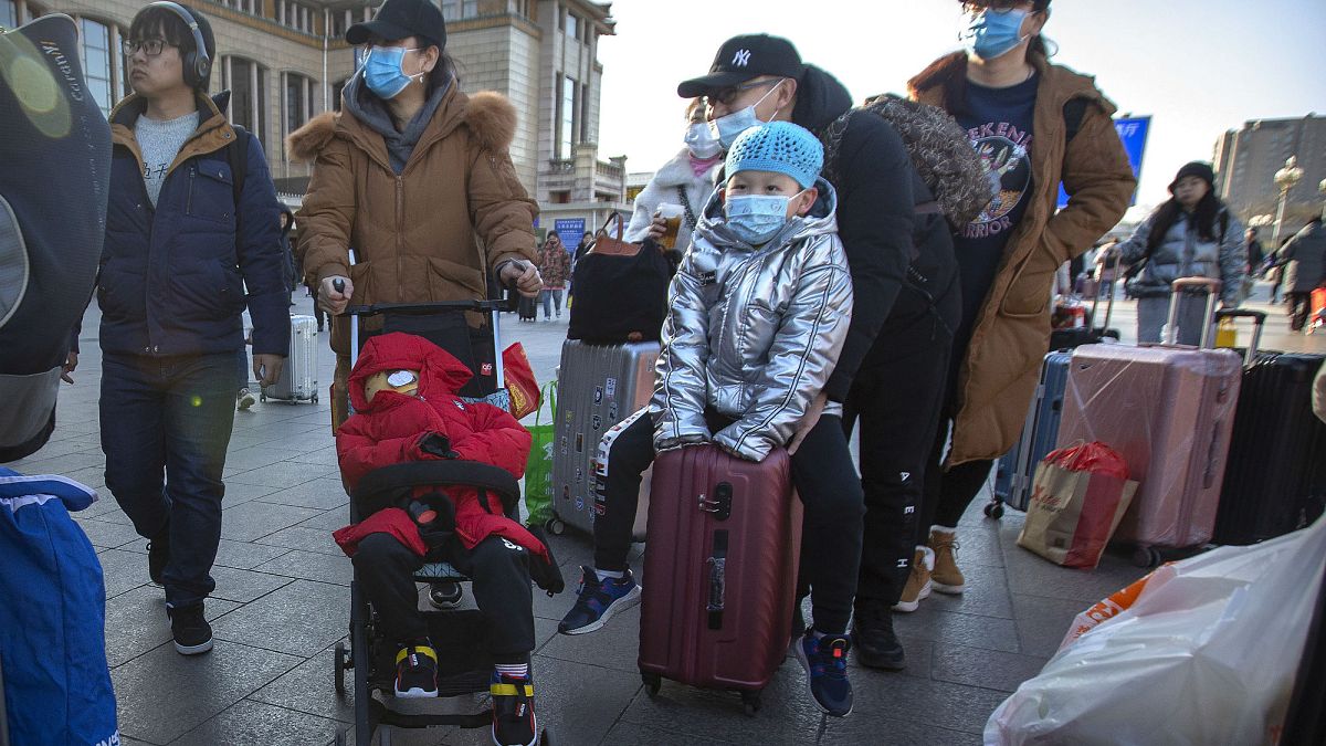 Pekin Tren İstasyonu'nda yolculuk yapan insanlar maske takıyor 