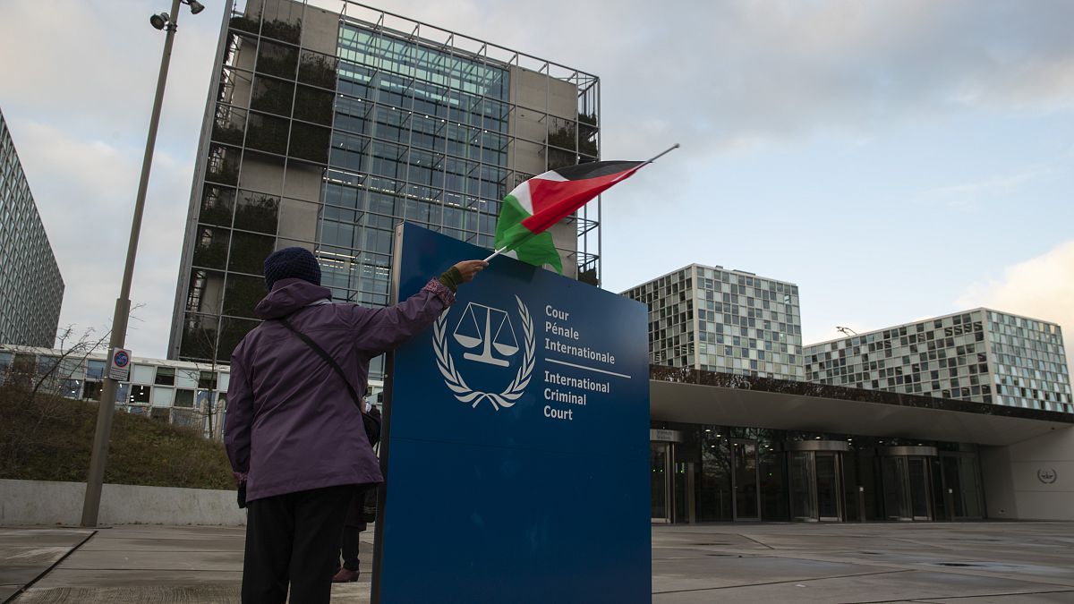 سيدة تحمل علم فلسطين أمام مبنى المحكمة الجنائية الدولية
