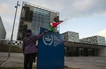 سيدة تحمل علم فلسطين أمام مبنى المحكمة الجنائية الدولية
