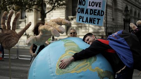 An Extinction Rebellion climate change protester hugs an inflatable planet Earth near Downing Street in London.