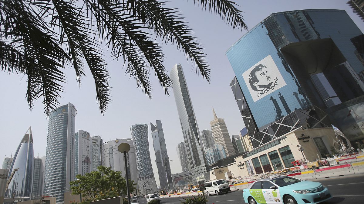 سيارة أجرة تمر بمبنى عليه صورة أمير قطر الشيخ تميم بن حمد آل ثاني في الدوحة، قطر.