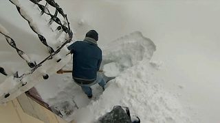 Mann schüppt Schneemassen vor seinem Haus