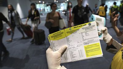 A health official holds a health alert card at the Soekarno-Hatta International Airport in Tangerang, Indonesia, Wednesday, Jan. 22, 2020