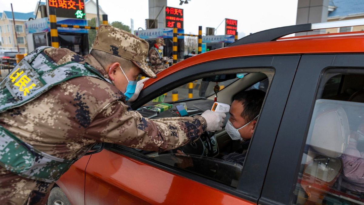 Contrôle de température par la police paramilitaire sur une barrière de péage d'une autoroute de Wuhan, le 23 janvier 2020.