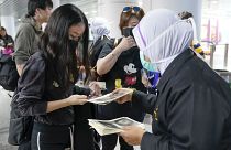 Agentes de inmigración dan información a viajeros en el aeropuerto de Kuala Lumpur
