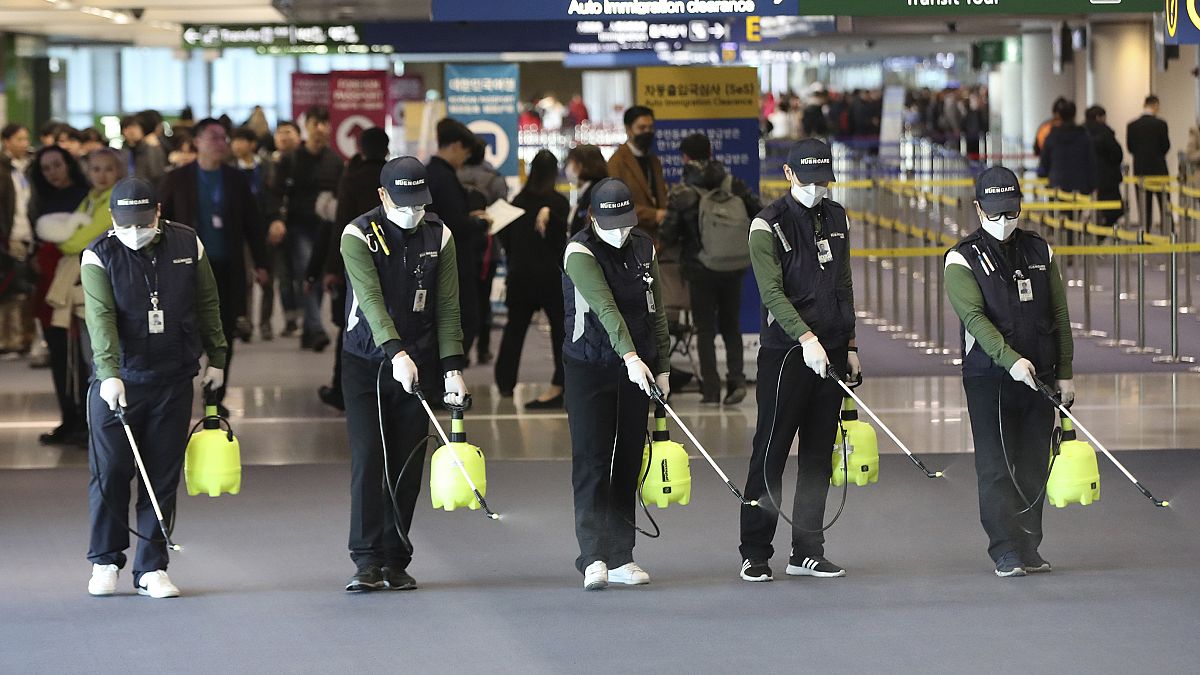 Güney Kore'de antiseptiklerle havaalanını temizleyen görevliler