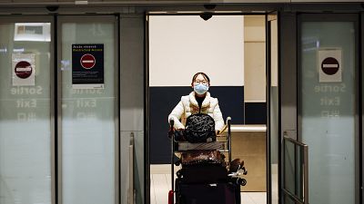 A traveler coming from Beijing and wearing a mask arrives at Charles de Gaulle airport, Paris.