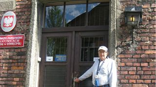 Siegmund Listwa, a Holocaust survivor, stands in front of his housing unit in Auschwitz, 2014.