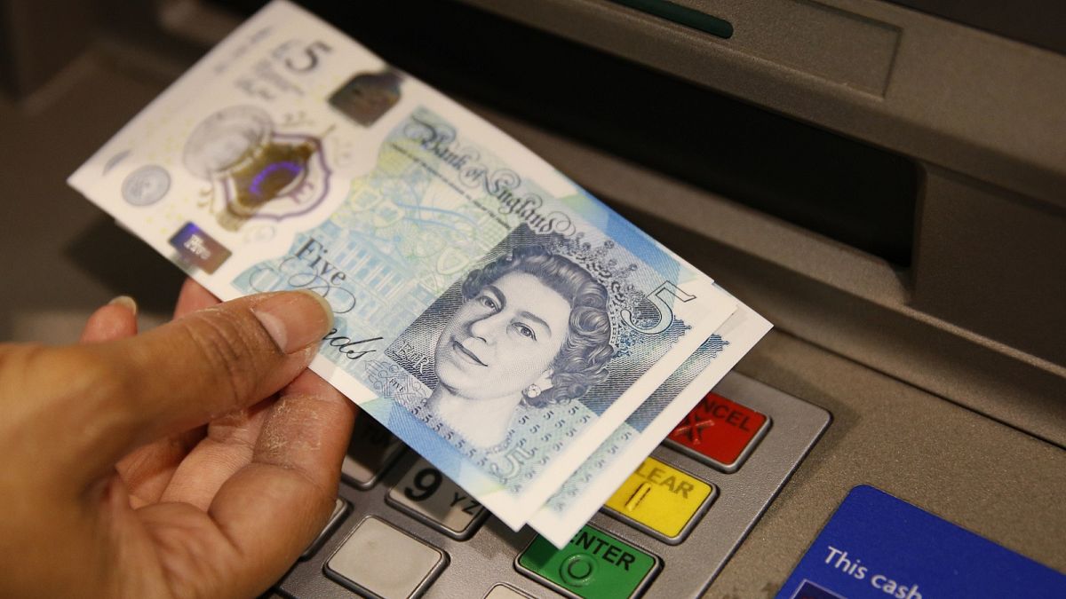 A member of staff at a branch of Halifax bank, in London, displays a new British 5 pound sterling note