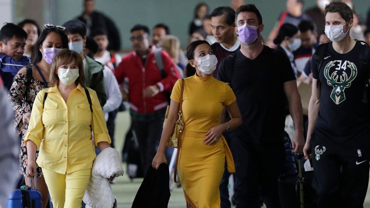 مسافرون يرتدون أقنعة عند وصولهم إلى مطار مانيلا الدولي في الفلبين.