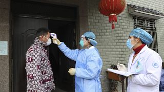 مسؤولو الصحة في الصين يقيسون درجة حرارة شخص للتأكد من عدم إصابته بفيروس كورونا