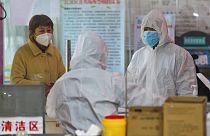 Medical workers in protective gear talk with a woman suspected of being ill with a coronavirus at a community health station in Wuhan in central China's Hubei Province
