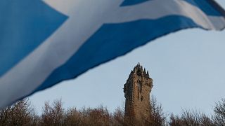 A Scottish Saltire flag blows in the wind near the Wallace Monument, Stirling, Scotland