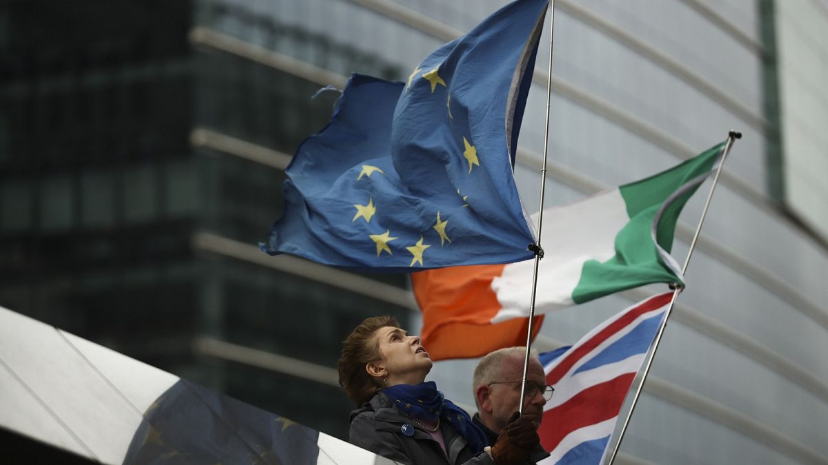 Two anti-Brexit people hold EU, Ireland and Union Flags stand outside the European Commission in Brussels, Friday, Oct. 11, 2019