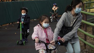 Children wearing masks, play in a park in Hong Kong, Friday, Jan. 31, 2020