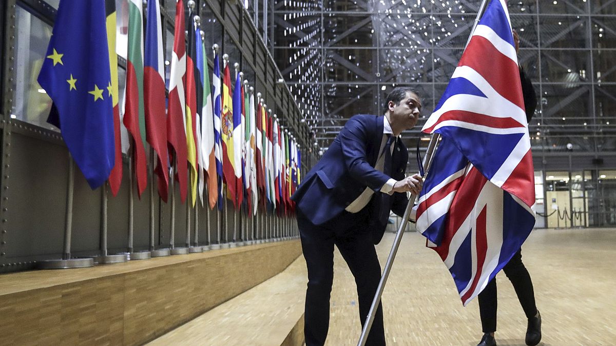 A member of protocol removes the Union flag from the atrium of the Europa building in Brussels, Friday, Jan. 31, 2020.