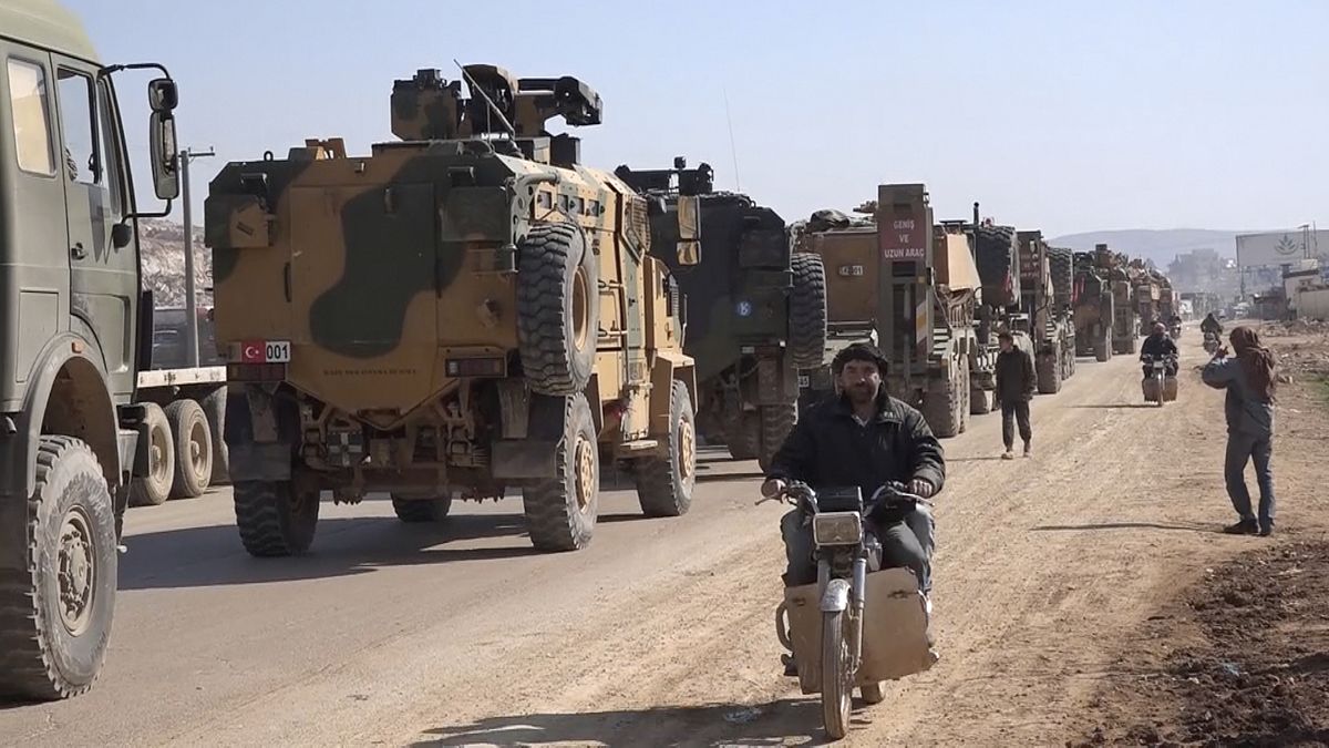 Screenshot - Sunday, Feb. 2, 2020, people ride their motorcycles next to a Turkey Armed Forces convoy is seen at the northern town of Sarmada, in Idlib province, Syria.