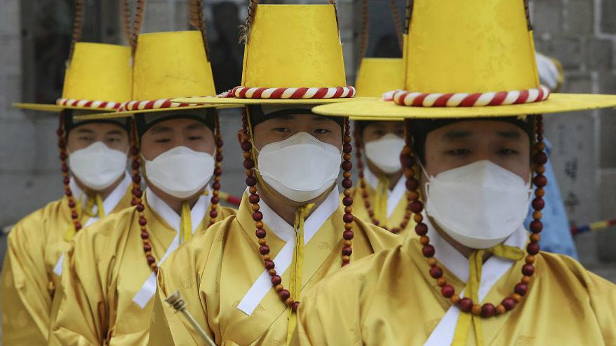 سربازان گارد امپراطوری در برابر کاخ سلطنتی کرهٔ جنوبی واقع در سئول ماسک تنفسی بر چهره دارند
