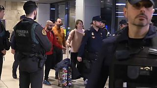 عناصر الأمن ترافق ركاب الطائرة إثر نزولهم في مطار مدريد.