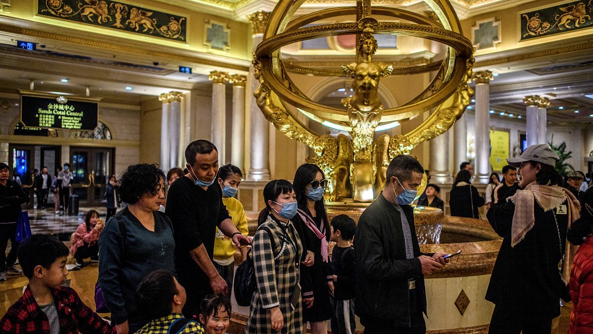 This file photo taken on January 22, 2020 shows visitors wearing face masks as they walk inside the Venetian casino hotel resort in Macau.