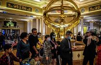 This file photo taken on January 22, 2020 shows visitors wearing face masks as they walk inside the Venetian casino hotel resort in Macau.