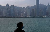 Hong Kong'un Victoria Harbour kıyısında maske giyen bir adam