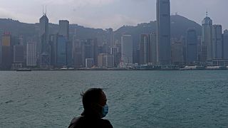 Hong Kong'un Victoria Harbour kıyısında maske giyen bir adam