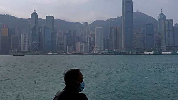 Hong Kong'un Victoria Harbour kıyısında maske giyen bir adam Hong Kong'un Victoria Harbour kıyısında maske giyen bir adam