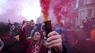 Football supporters set off flares before the English Premier League soccer match between Liverpool and Manchester United near Anfield Stadium in Liverpool.