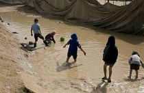 FILE - In this March 31, 2019 file photo, children play in a mud puddle in the section for foreign families at Al-Hol camp in Hasakeh province, Syria.