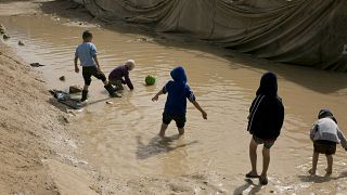 FILE - In this March 31, 2019 file photo, children play in a mud puddle in the section for foreign families at Al-Hol camp in Hasakeh province, Syria.
