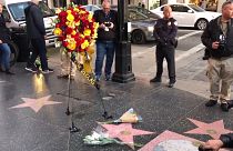 Hollywood Walk of Fame star of actor Kirk Douglas, with wreath of flowers on stand and two bouquets of flowers on ground