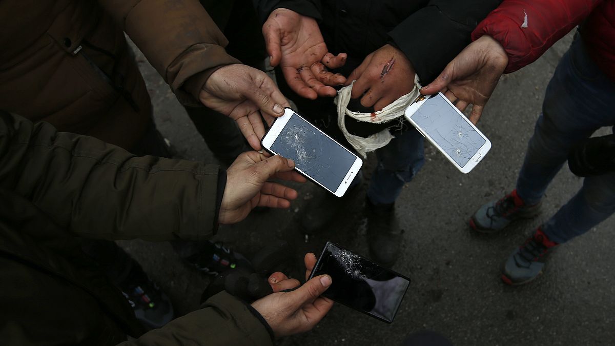 Un gruppo di migranti mostra i telefoni distrutti nel villaggio di Horgos, Serbia, nel gennaio 2020. Siamo vicino al confine ungherese